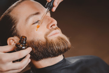 Oil for beard in dropper, process of moisturizing hair.