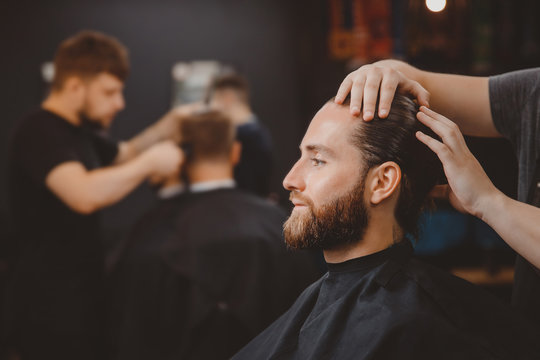 Barber shop. Man in barbershop chair, hairdresser styling his hair