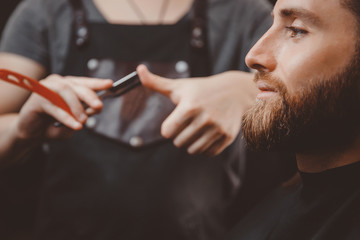 Barber process shaving razor bearded hipster man in barbershop.