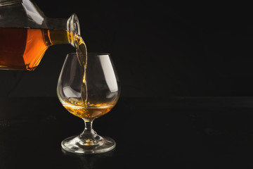Pouring brandy or cognac from bottle into glass