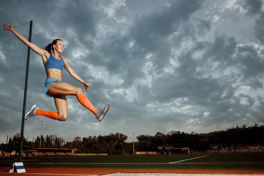 Female athlete performing a long jump during a competition at stadium. The jump, athlete, action, motion, sport, success, championship concept