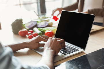 Young man working using laptop in the kitchen