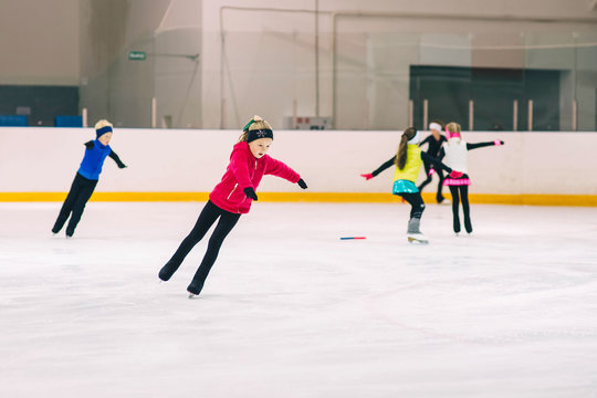 Little girl learning to ice skate. Figure skating school. Young figure skater practicing at indoor skating rink.