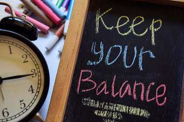 Keep your balance on phrase colorful handwritten on chalkboard, alarm clock with motivation and...