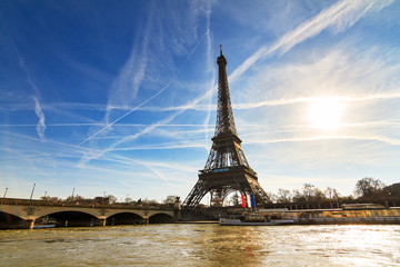 Beautiful backlit Eiffel tower at the Seine river with a dramatic sky in winter