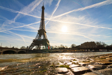 Beautiful backlit Eiffel tower at the Seine river with a dramatic sky in winter