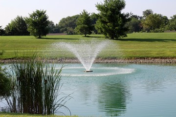 The flowing water fountain in the park on a sunny day.