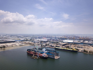 Fototapeta na wymiar Aerial view of logistics concept floating dry dock servicing cargo ship and commercial vehicles, cars and pickup trucks waiting to be load on to a roll-on/roll-off car carrier ship at Laem Chabang 