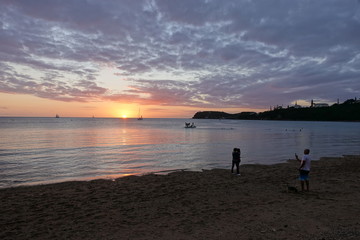 南国の夕日を背に写真を取る人々