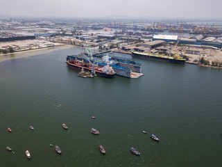 Fototapeta na wymiar Aerial view of logistics concept floating dry dock servicing cargo ship and commercial vehicles, cars and pickup trucks waiting to be load on to a roll-on/roll-off car carrier ship at Laem Chabang 