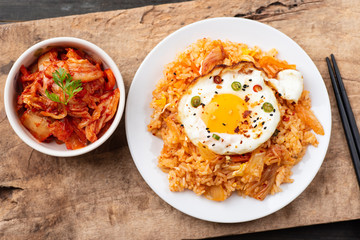 Kimchi fried rice with fried egg on top and fresh kimchi cabbage in a bowl, top view, Korean food