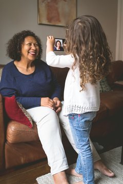 Girl Taking Picture Of Grandmother On Mobile Phone