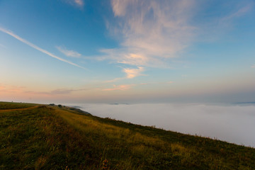 Sunrise landscape. Early morning slopes covered with heavy fog