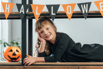 portrait of smiling kid looking at camera in decorated room for halloween