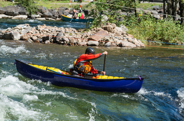 Paddling a whitewater equipped canoe through the rapids .