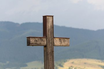 Simple oak catholic cross close up shot, pine woods in the background .
