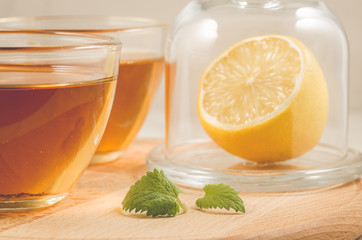 tea with a lemon and mint in glass/tea with a lemon and mint in glass on a wooden table