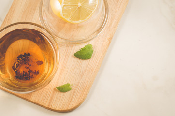 tea with a lemon and mint in glass/tea with a lemon and mint on a wooden tray on white marble. Top view and copy space