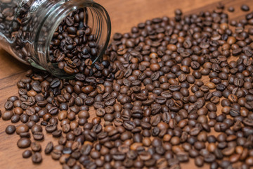 Coffee beans, poured from a glass transparent jar.