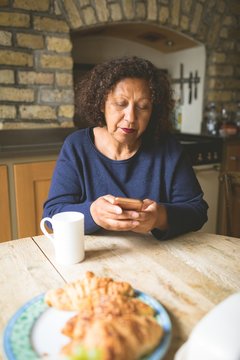 Senior woman using mobile phone in kitchen
