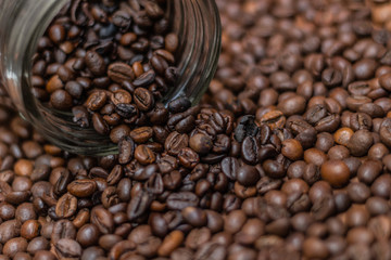 Coffee beans, poured from a glass transparent jar.