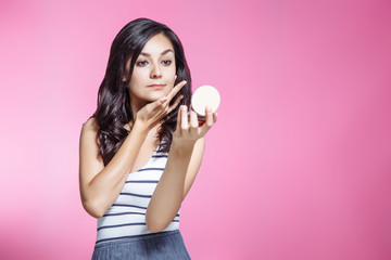 Portrait of beautiful young woman with mirror on pink background.