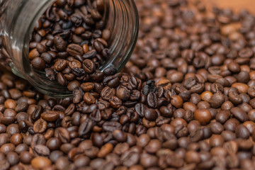 Coffee beans, poured from a glass transparent jar.