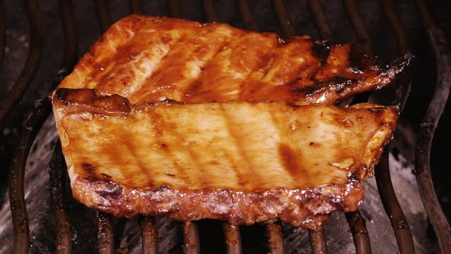 UHD closeup shot of marinated spare ribs cooking on a barbecue grill