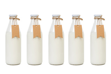 Botellas de leche con etiquetas sobre un fondo blanco liso y aislado. Vista de frente y de cerca....