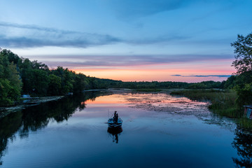 fishermen and boat silhouetted in sunset on the river