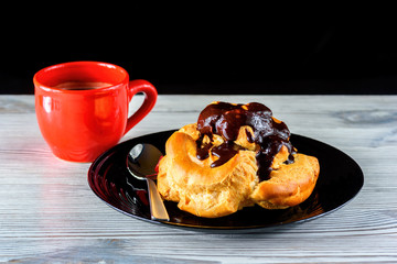 home eclair on a plate and a mug with coffee on a wooden background 
