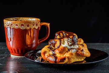 home eclair on a plate and a mug with coffee on a wooden background 