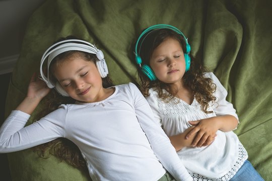Siblings listening music while relaxing in bedroom
