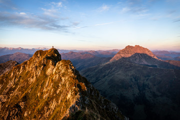 Bergsteiger steht beim Sonnenaufgang am Gipfel