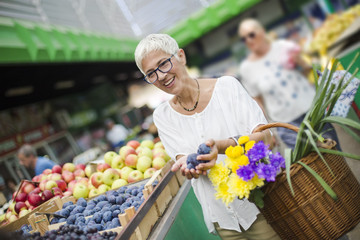Senior woman buying fruit on market