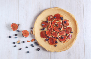 Dough tart with figs and berries  on a wooden table. Top View