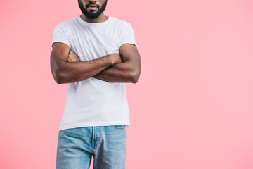 partial view of african american man with arms crossed in casual clothing isolated on pink