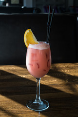 Glass of Sex on the Beach cocktail and shaker against black background