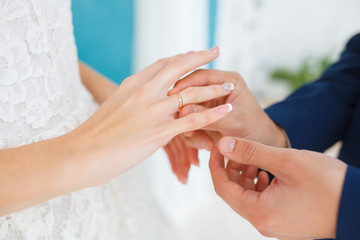The groom carefully puts the ring on the finger of the future wife