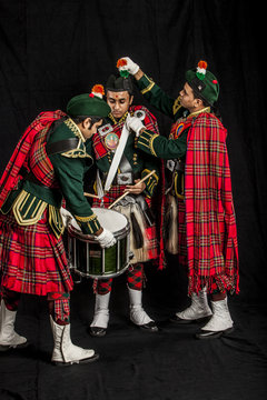 Two pipers and snare drummer of an Indian American Scottish bagpipe band in full Scottish regalia, including kilts and sporrans getting ready for a performance