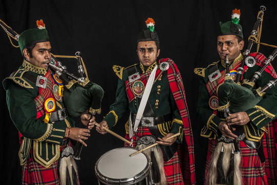 Two pipers and snare drummer of an Indian American Scottish bagpipe band in full Scottish regalia, including kilts and sporrans