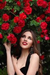 Naklejka premium Portrait of beautiful young woman in the rose garden, spring time, rose flowers blossoms.