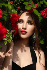 Portrait of  beautiful young woman in the rose garden, spring time, rose flowers blossoms.