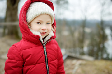 Adorable little girl having fun on beautiful winter day in a city. Cute child having a walk in winter town.