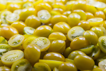 A lot of sliced fresh yellow tomatoes on a table in the kitchen