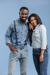 happy african american couple hugging and looking at camera isolated on blue