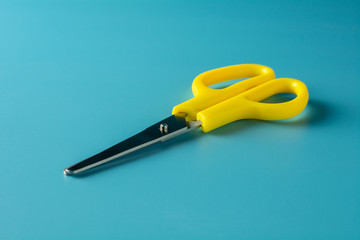 yellow plastic scissors on blue paper. - background