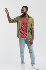 smiling handsome african american man waving hand and looking away isolated on white