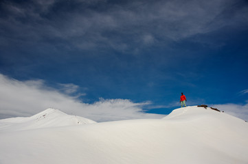 a guy stands on the snow-covered mountain, against the sky