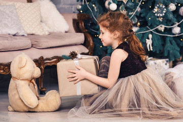 Red-haired girl gives Christmas gift to teddy bear.